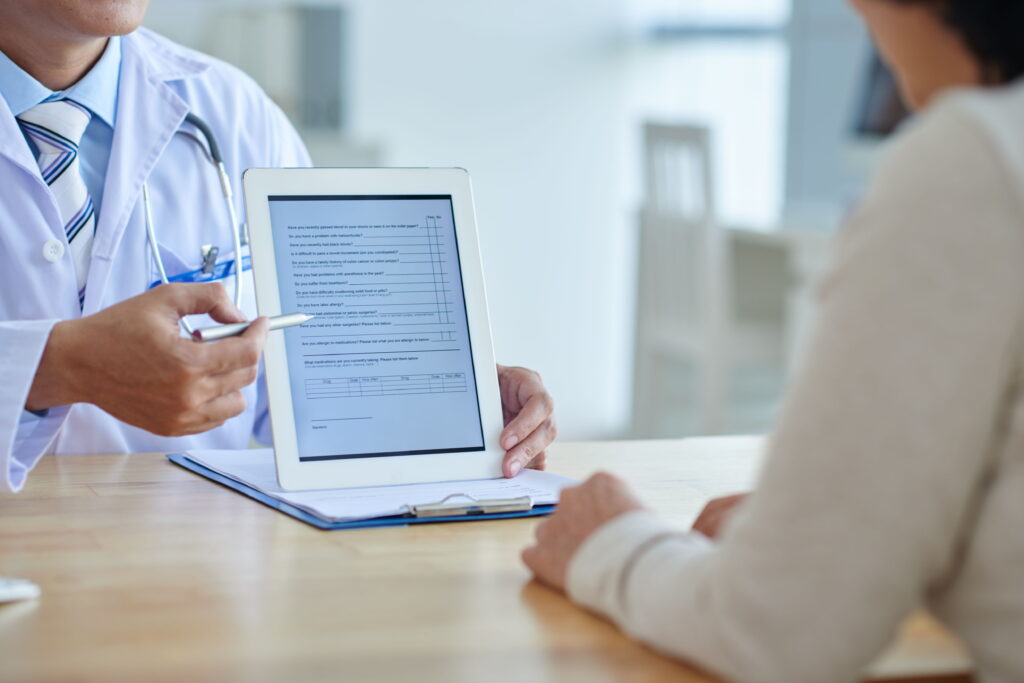 Profissional de saúde mostrando para paciente em tablet eletrônico termos de um documento para assinatura digital na telemedicina.